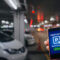 pick me up, mobile smart phone in hand using application for intelligent car park on blurred parking car indoor background,  mobile auto parking, online technology and internet connection concept